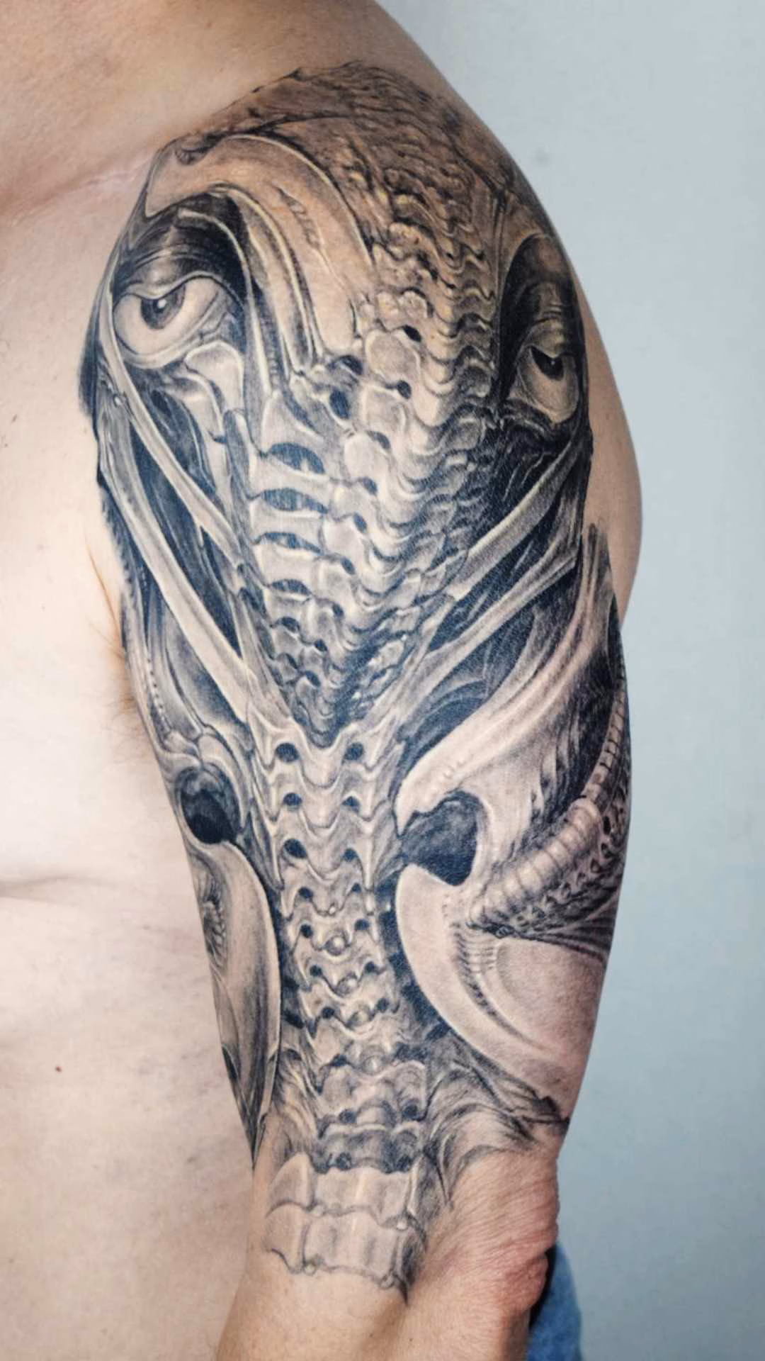 Tattoo von einem an H.R.Giger angelehnten Gesicht, das aus Knochen, Strukturen und Wirbelsäule Elementen in Biomechanik besteht