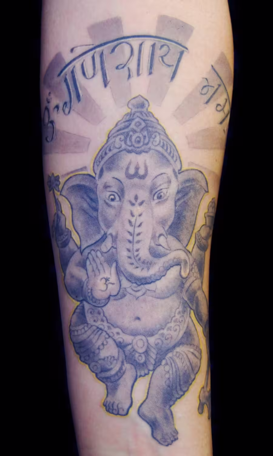 Spirituelles Ganesha Tattoo mit Hindi-Mantra in Halbkreisform über dem Kopf, detailreiche Darstellung der Hindu-Gottheit von Raul bei Hits for Life München