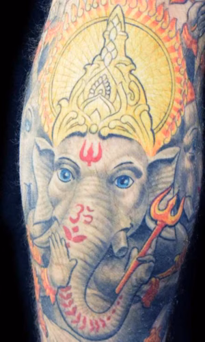 Spirituelles Trimukha Ganapati Tattoo mit drei Köpfen und 18 Armen, detailreiche Darstellung des dreigesichtigen Elefantengotts von Raul bei Hits for Life München.