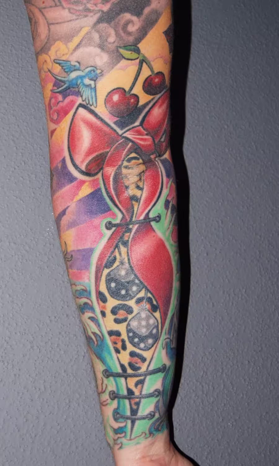 Rockabilly Old-School Tattoo mit Glaube-Liebe-Hoffnung-Symbolen, Schleife im Leopardenmuster, Würfeln und Kirschen, traditionelles Design von Raul bei Hits for Life München