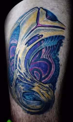 Organisches Biomechanik Tattoo am Oberschenkel mit integrierter Fleur-de-Lis, fließende anatomische Strukturen kombiniert mit heraldischer Symbolik von Raul, München
