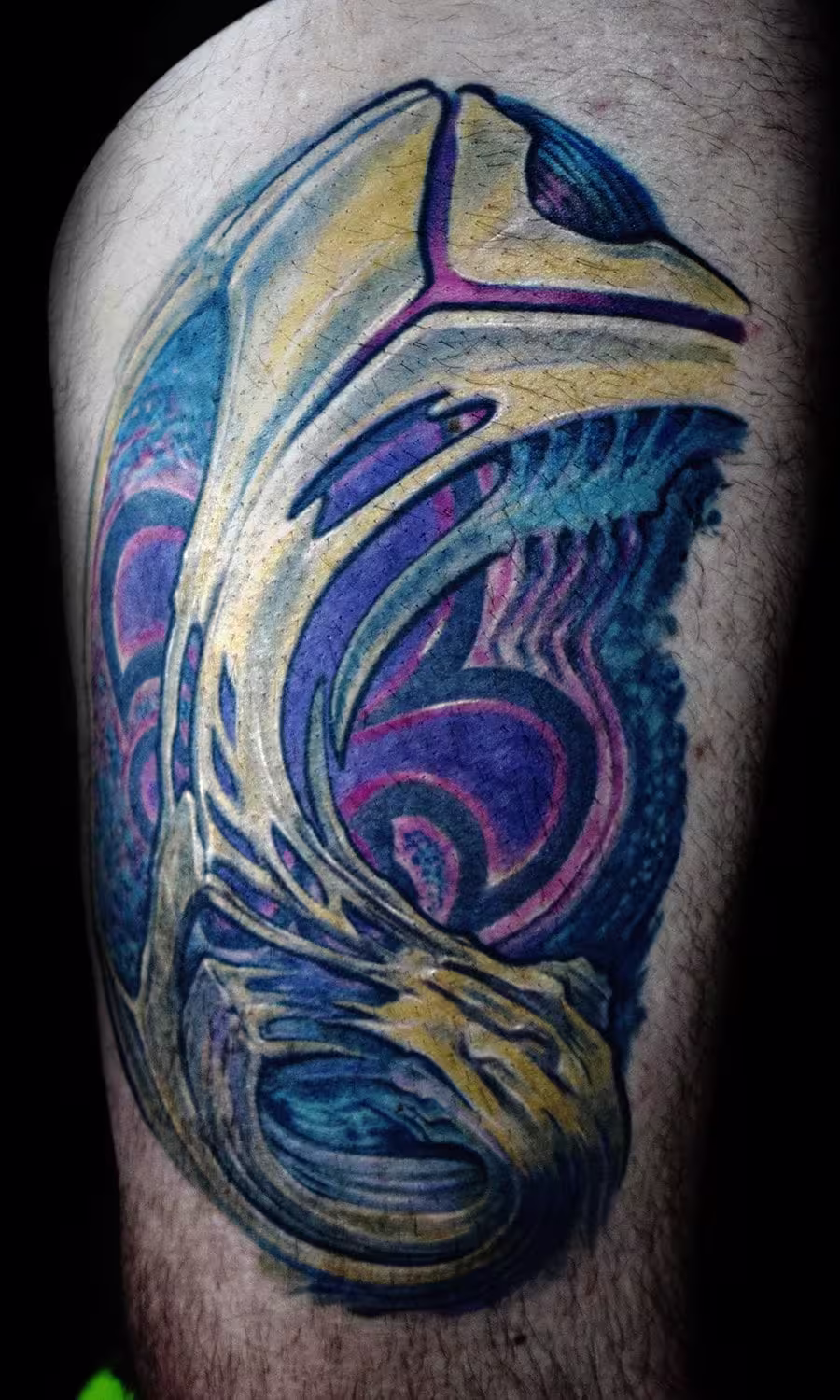 Organisches Biomechanik Tattoo am Oberschenkel mit integrierter Fleur-de-Lis, fließende anatomische Strukturen kombiniert mit heraldischer Symbolik von Raul, München