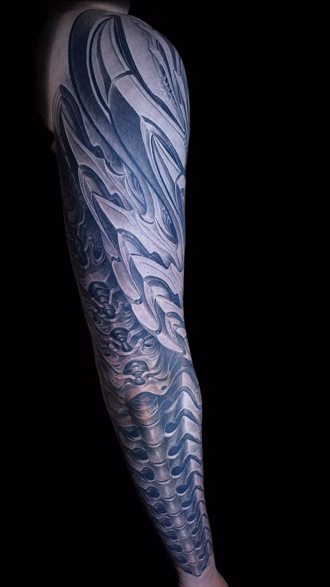 Morphendes Biomechanik Rüstungs-Fullsleeve tattoo Detailansicht des Unterarms mit einer exakt entlang der Längsachse ausgerichteten, wirbelkörperartigen Struktur im Black-and-Grey-Stil