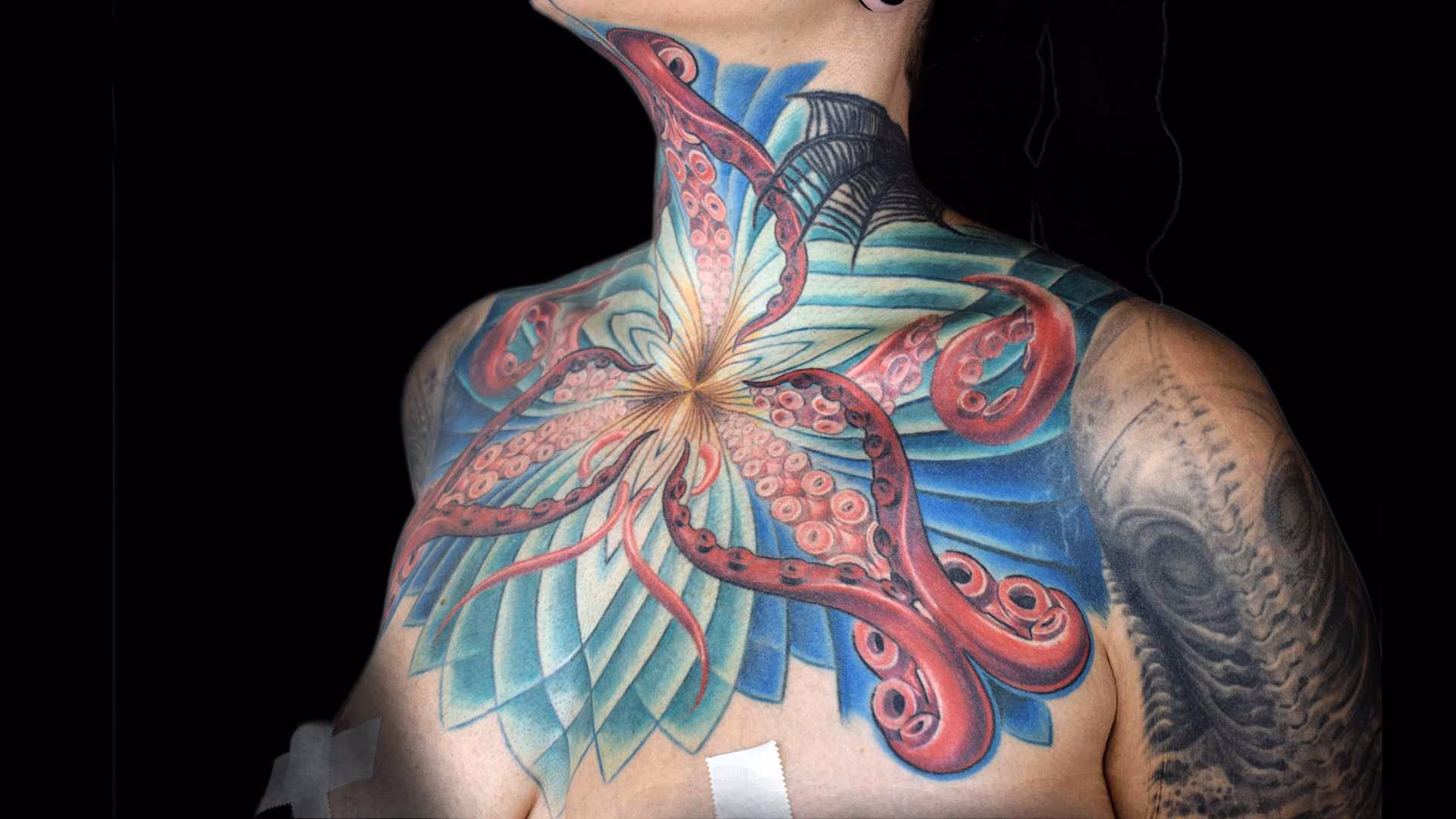 Ste Hypnotisches Female Chest Tattoo mit integriertem Hals-Tattoo von Roald Beyer. Florales Dotwork-Mandala in Blau-Türkis mit roten Octopus-Sucker-Tentakeln, gestochen in Taufkirchen bei München