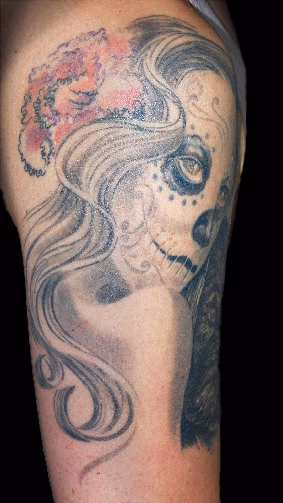 La Catrina Detailansicht der weich schattierten La Catrina mit farbigen Augen, farbiger Nase und einer stilisierten Nelke im Haar. Fließende Haare leiten das Tattoo nach hinten sanft aus