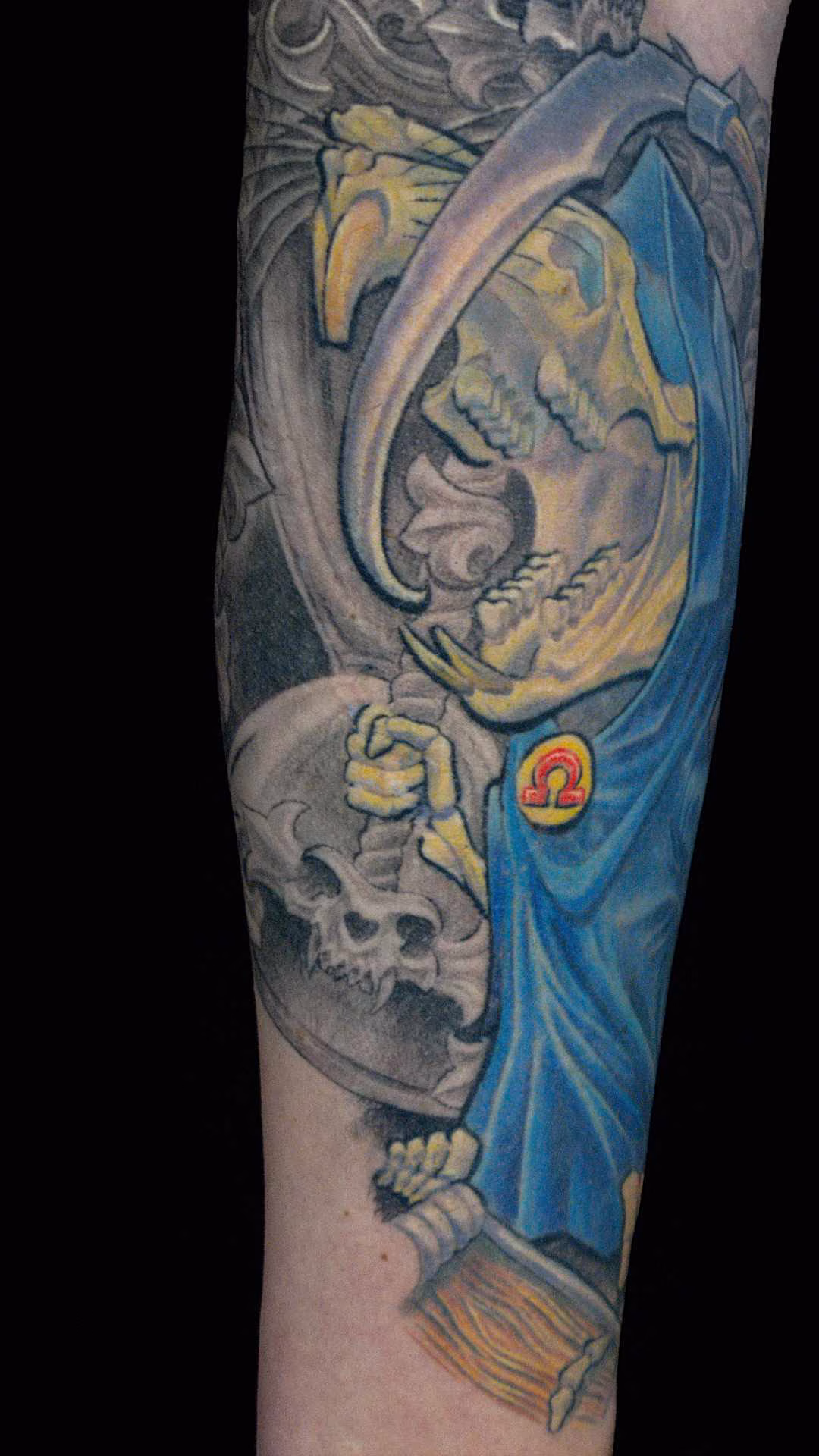 Grim Squeaker Tätowierung des lachenden Rattentods (Grim Squeaker) mit einer mit Katzenschädel verzierten Sanduhr und Sense, frei nach Terry Pratchetts Scheibenwelt auf dem Unterarm, anatomisch angepasst auf den Muskulus brachioradialis