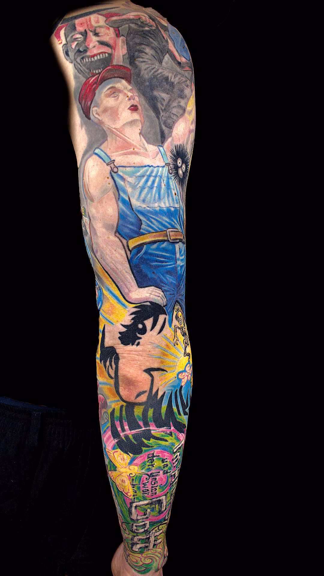 Flucht aus Berlin Tattoo Sleeve Wimmelbild Nietsche Historia in Rückansicht Fullsleeve Tattoo mit heroischer Arbeiterfigur, tanzendem Yue-Minjun-Charakter und anatomisch angepasstem Nietzsche-Konterfei über dem Ellbogen